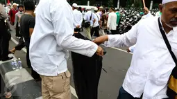 Massa membuang sampah ke kantong plastik yang disediakan oleh relawan di tengah aksi damai 4 November di Jakarta, Jumat (4/11). Mereka mengumpulkan sampah berupa bekas botol minuman dan bungkus nasi yang dibuang anggota ormas (Liputan6.com/Faizal Fanani)