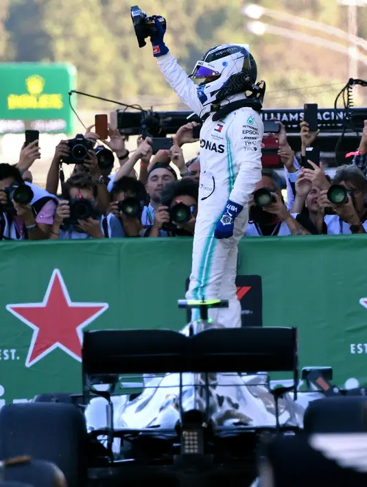 Pembalap Mercedes, Valtteri Bottas berselebrasi di atas mobilnya setelah menjuarai balapan Formula 1 (F1) GP Jepang di Sirkuit Suzuka, Minggu (13/10/2019). Bottas sukses mengungguli pembalap Ferrari, Sebastian Vettel dan pembalap Mercedes Lewis Hamilton . (Toshifumi KITAMURA/AFP)