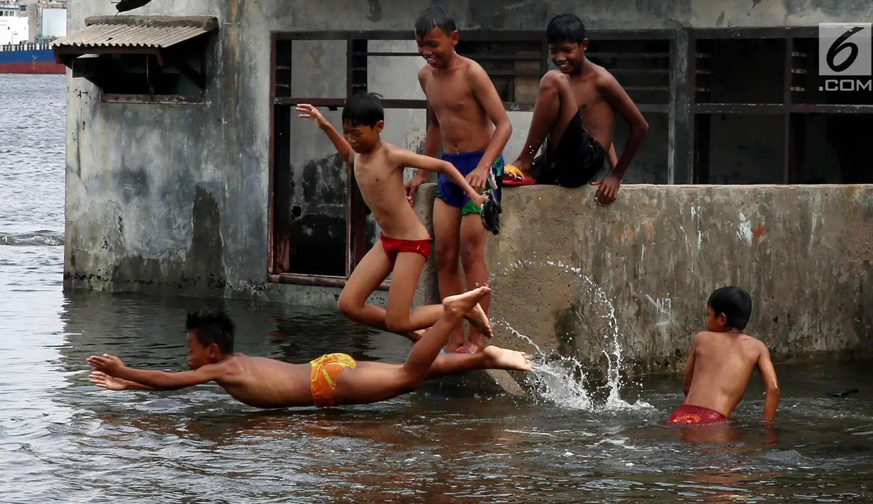 Seorang anak melompat saat bermain di Masjid yang terkena Abrasi di kawasan Muara Baru, Jakarta, Kamis (4/1). Anak-anak yang bermukim di kawasan tersebut banyak menghabiskan waktu saat berlibur sekolah untuk bermain di laut. (Liputan6.com/Johan Tallo)