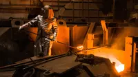 Seorang pekerja mengenakan pakaian pelindung mengambil cairan untuk membuat baja di Salzgitter, Jerman (22/3). Baja dibuat‎ dari hasil peleburan pasir besi, batu bara dan kapur dengan suhu di atas 1.000 derajat celciu‎s. (AP Photo / Markus Schreiber)