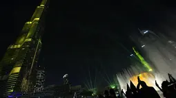 Pengunjung mengambil gambar pertunjukan sinar laser dari menara tertinggi dunia, Burj Khalifa, di Dubai, 31 Desember 2017. Pertunjukkan ini memecahkan rekor dunia Guinness dengan pertunjukan Light Up 2018 termegah di Malam Tahun Baru (Giuseppe CACACE/AFP)