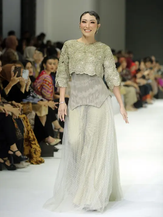 Istri Regi Datau itu terlihat mengenakan crop top bordiran bunga kenanga yang dipadukan korset corak ulos dan rok tulle serba hijau sage. [Fimela/Bambang E. Ros]