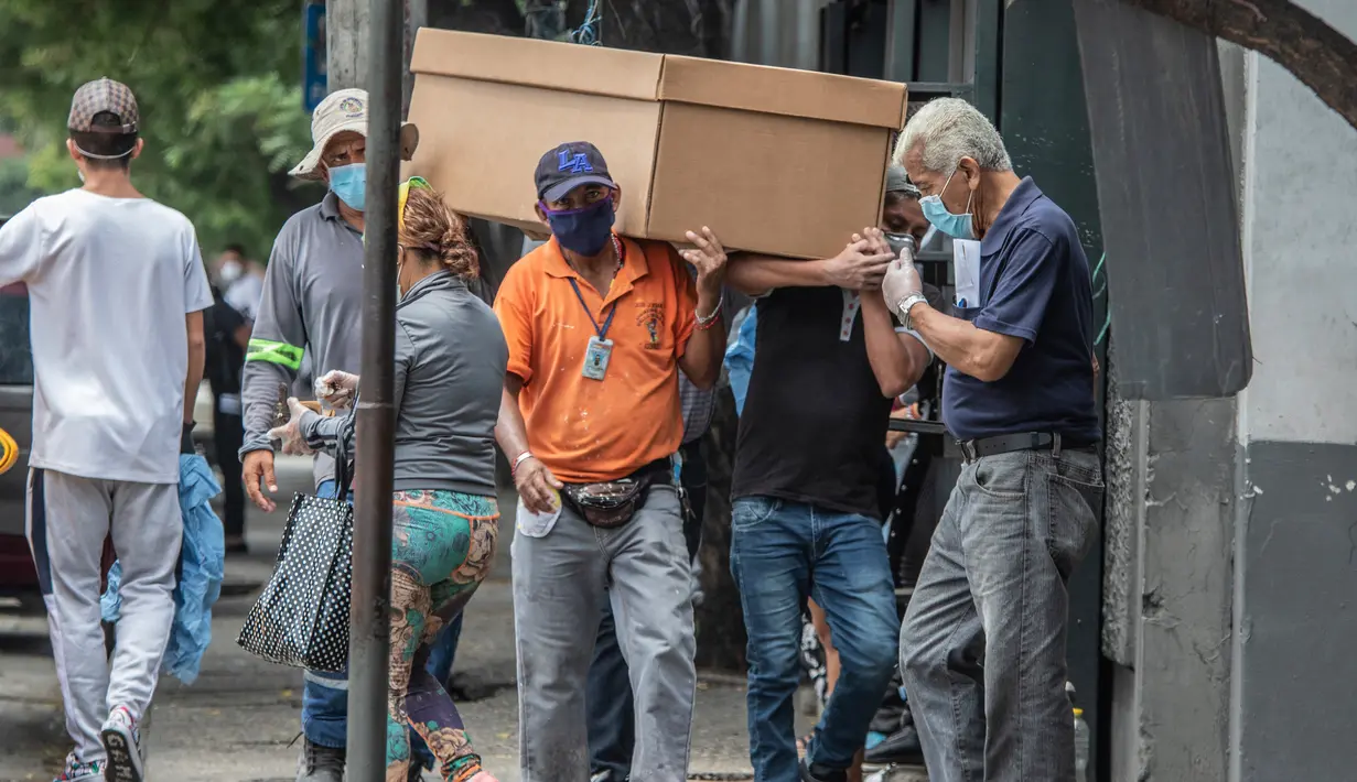 Pekerja makam membawa jenazah dalam peti mati kardus untuk dimakamkan di Pemakaman Umum di Guayaquil, Ekuador, Senin (6/4/2020). Kehabisan peti mati, kota terbesar di Ekuador yang menjadi klaster wabah virus corona itu terpaksa menggunakan kotak kardus untuk korban Covid-19. (AP/Luis Perez)