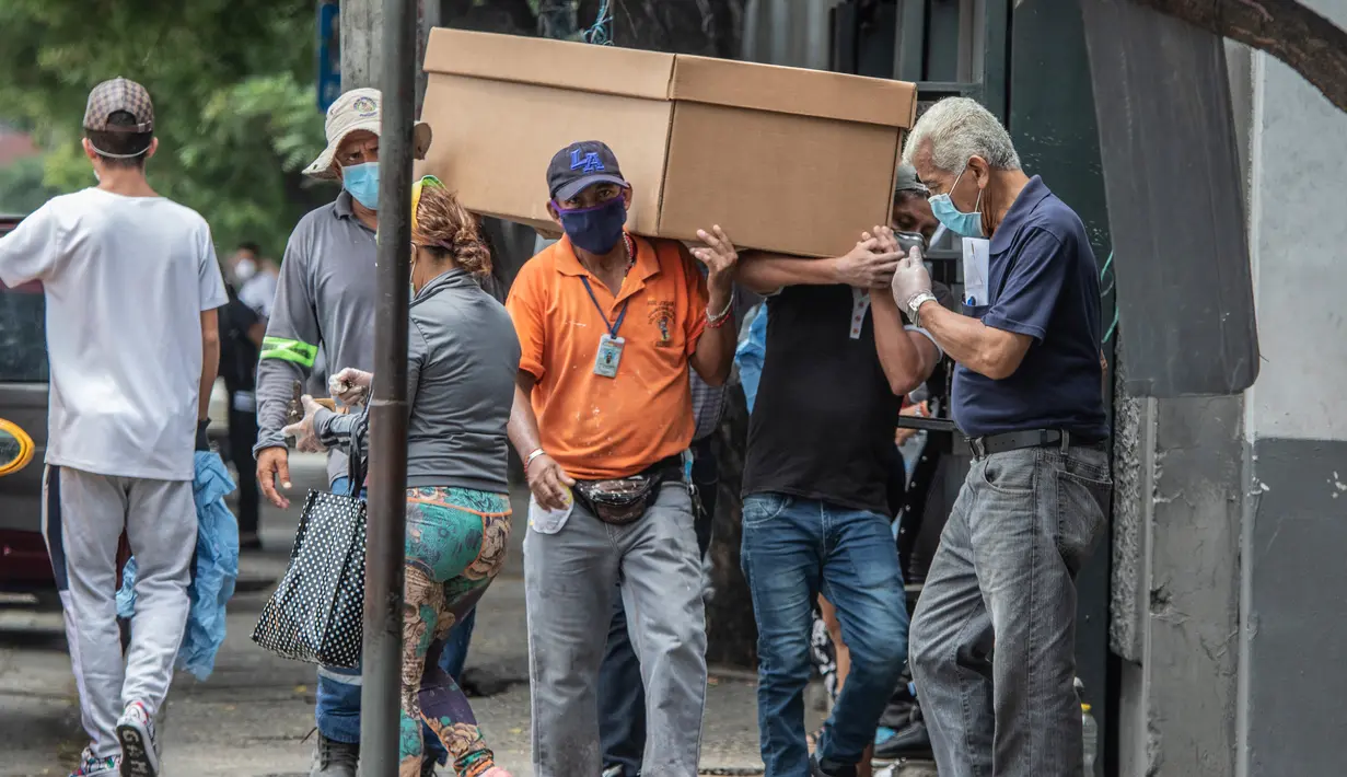Pekerja makam membawa jenazah dalam peti mati kardus untuk dimakamkan di Pemakaman Umum di Guayaquil, Ekuador, Senin (6/4/2020). Kehabisan peti mati, kota terbesar di Ekuador yang menjadi klaster wabah virus corona itu terpaksa menggunakan kotak kardus untuk korban Covid-19. (AP/Luis Perez)