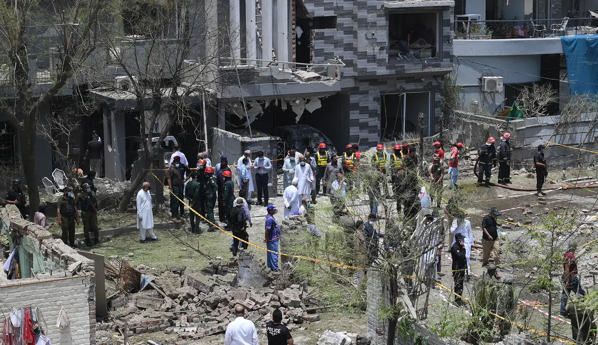 Petugas polisi, penyelidik, dan petugas penyelamat berkumpul di lokasi ledakan, di Lahore, Pakistan, Rabu (23/6/2021). Ledakan itu terjadi sekitar 120 meter dari kediaman Hafiz Saeed di Lahore, menurut laporan. (AFP/Arif Ali)