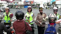 Sejumlah polwan dari jajaran Polda DIY mengajak warga mencintai mereka lewat pembagian bunga dan cokelat di Tugu Yogyakarta. (Liputan6.com/Switzy Sabandar)