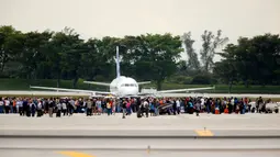 Penumpang dievakuasi di landasan pesawat saat penembakan di Bandara Fort Lauderdale, Florida, AS (6/1). Menurut polisi, pelaku penembakan tiba dari penerbangan Kanada dan tengah melakukan pemeriksaan bagasi kedatangan. (Al Diaz /Miami Herald via AP)
