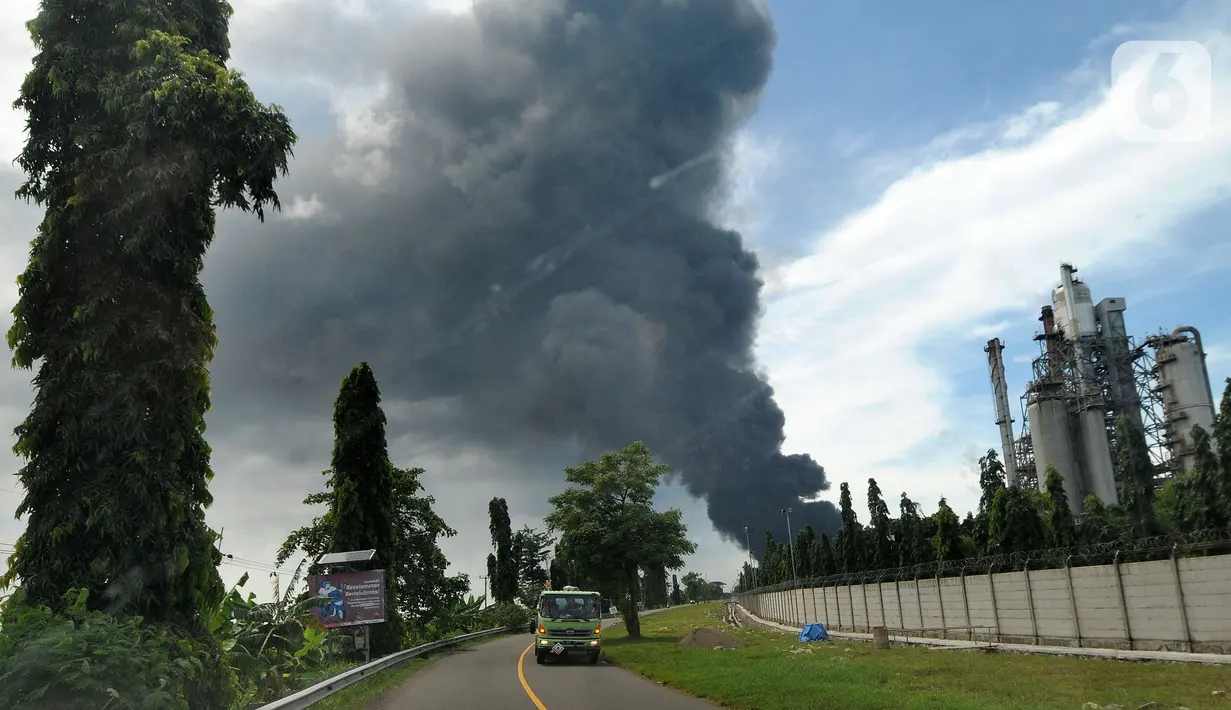 Kendaraan melintas dengan latar belakang kepulan asap akibat kebakaran Kilang Balongan di Indramayu, Jawa Barat, Senin (29/03/2021). Dampak dari terbakarnya kilang minyak Balongan milik PT Pertamina itu mengakibatkan Jalan Raya Balongan-Indramayu ditutup total. (merdeka.com/Arie Basuki)
