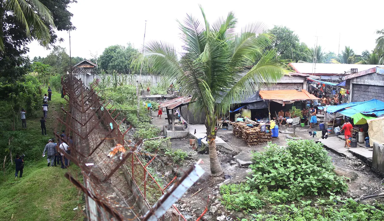 Aparat kepolisian (kiri) memeriksa pagar parimeter penjara menyusul serangan sekelompok pria bersenjata di kota Kidapawan, selatan Filipina, Rabu (4/1). Mereka menembaki seorang penjaga dan membebaskan 158 dari 1.511 tahanan. (Ferdinandh CABRERA/AFP)