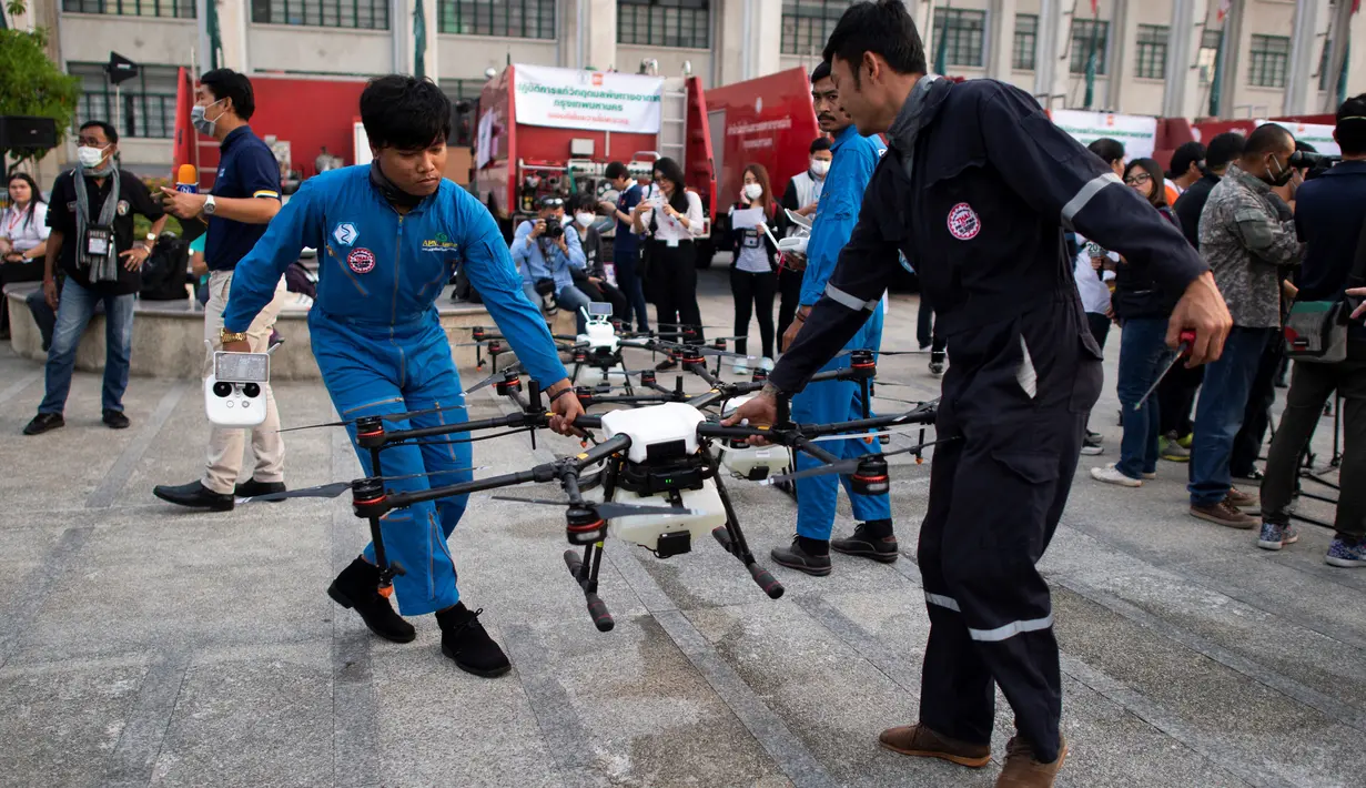Dua relawan membawa drone untuk menurunkan hujan buatan selama demontrasi di Bangkok, Kamis (31/1). Operasi pengurangan polusi udara dilakukan dengan menggunakan drone untuk menurunkan hujan buatan dengan cara menyemprotkan bahan kimia. (Jewel SAMAD/AFP)