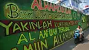 Pengendara melintasi mural bernuansa Islami di Gang Pelangi, kawasan Kalibata, Jakarta, Jumat (23/4/2021). Mural bernuansa Islami tersebut dibuat untuk menghiasi dan meramaikan pintu masuk gang sekaligus mengingatkan masyarakat untuk selalu beribadah dan bershalawat (Liputan6.com/Herman Zakharia)