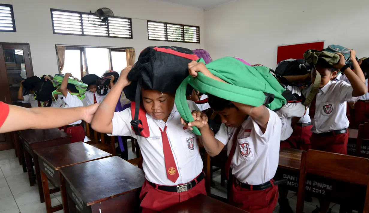 Sejumlah siswa SD menggunakan tas sekolah mereka untuk melindungi diri selama latihan tsunami di Tanjung Benoa dekat Denpasar di pulau resor Bali (15/8). (AFP Photo/ Sonny Tumbelaka)