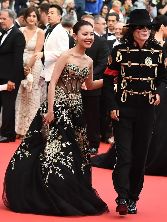 Seorang pria berpenampilan Michael Jackson didampingi wanita cantik menghadiri pemutaran film Solo: A Star Wars Story di Festival Film Cannes, Prancis, Selasa (15/5). Belum diketahui dengan pasti siapa pria tersebut. (AFP/Anne-Christine POUJOULAT)