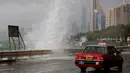 Sebuah taksi melintas di dekat ombak besar yang menghantam pesisir Hong Kong, Tiongkok, Jumat (21/10). Akibat terjangan angin berkecepatan 160 kilometer per jam itu, sedikitnya 700 penerbangan di Hongkong ditunda atau dibatalkan. (REUTERS/Bobby Yip)