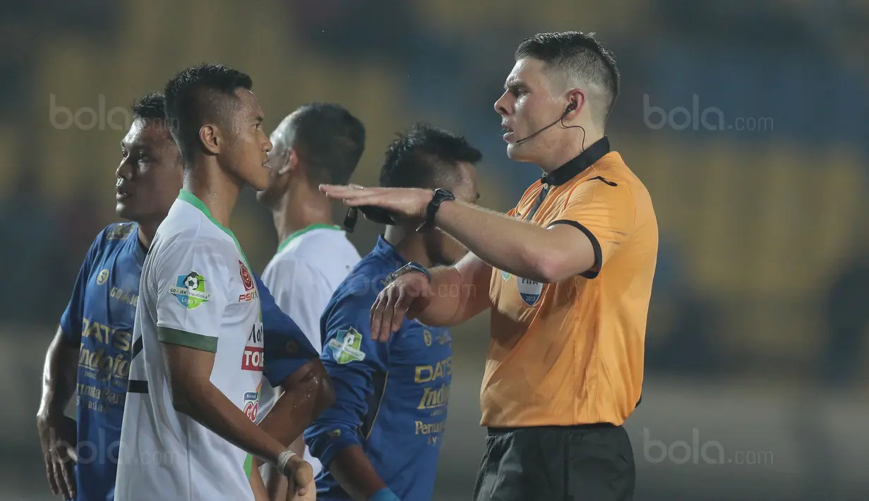 Wasit Evan Shaun Robert memberikan mencoba memberikan penjelasan kepada pemain PS TNI, Sansan Husaeni saat laga melawan Persib Bandung pada lanjutan Liga 1 2017 di Stadion Si Jalak Harupat, Sabtu (05/8/2017). (Bola.com/Nicklas Hanoatubun)