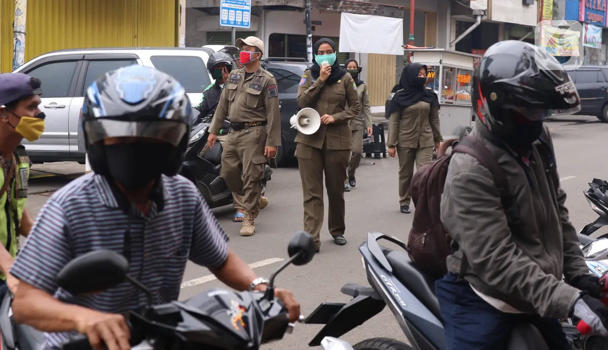 Petugas Satpol PP mengimbau warga untuk menggunakan masker dan menjaga jarak di Pasar Lama, Kota Tangerang, Banten, Sabtu (9/6/2020). Pemkot Tangerang melakukan penegasan pada PSBB tahap dua dengan menugaskan petugas di keramaian guna memutus rantai penyebaran COVID-19.  (Liputan6.com/Angga Yuniar)