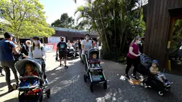 Keluarga memasuki Kebun Binatang Taronga di Sydney (18/10/2021). Kebun binatang Taronga membuka kembali pintunya bagi pengunjung yang divaksinasi setelah pencabutan pembatasan penguncian Sydney. (AFP/Saeed Khan)