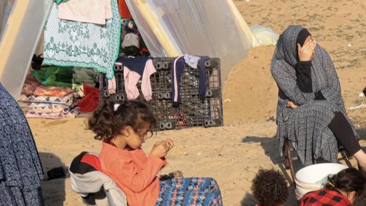 Warga Palestina dari Khan Younnis terlihat duduk dikelilingi barang-barang bawaannya setelah sampai di Rafah.