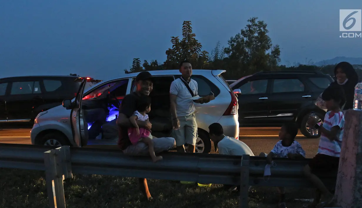 Pemudik menikmati makanan untuk berbuka puasa sembari beristirahat di pinggir ruas jalan tol Cipali KM 187, Kabupaten Cirebon, Jawa Barat, Kamis (30/5/2019). Sejumlah pemudik memilih menggunakan bahu jalan ruas tol untuk berbuka puasa karena penuhnya rest area. (Liputan6.com/Herman Zakharia)