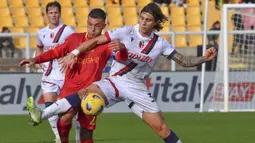 Pemain Lecce, Gabriel Strefezza (kiri) berebut bola dengan pemain Bologna, Riccardo Calafiori saat laga pekan ke-14 Liga Italia 2023/2024 di Via del Mare Stadium, Lecce, Italia, 3 Desember 2023 waktu setempat. Laga berakhir imbang dengan skor 1-1. (AP Photo/LaPresse/Giovanni Evangelista)