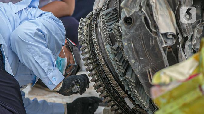 Petugas Komisi Nasional Keselamatan Transportasi (KNKT) memeriksa bagian turbin pesawat Sriwijaya Air dihari kelima yang jatuh di perairan Pulau Seribu, di Dermaga JICT, Jakarta,  Rabu (13/1/2021). Pemeriksaan itu dilakukan untuk mengetahui penyebab jatuhnya pesawat. (/Faizal Fanani)