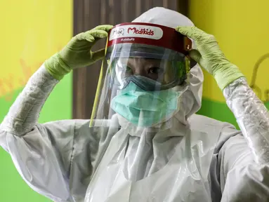 Dokter menggunakan APD akan memeriksa gigi pasien anak di klinik Medikids kawasan Kemang, Jakarta Selatan, Selasa (7/7/2020). Pelayanan dokter gigi dengan menggunakan APD lengkap untuk memenuhi protokol kesehatan guna mencegah penyebaran covid-19 di era kenormalan baru. (Liputan6.com/Faizal Fanani)