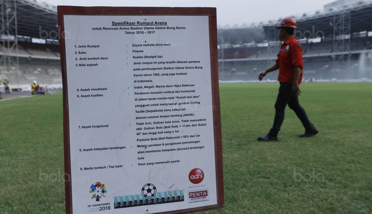 Pekerja melintas di depan papan spesifikasi rumput  di SUGBK, Senayan, Jakarta, Selasa (8/8/2017). SUGBK menggunakan rumput jenis Zoysia matrella yang merupakan rumput standar FIFA untuk stadion bertaraf internasional. (Bola.com/M Iqbal Ichsan)