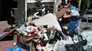 Seorang wanita pengendara motor melewati tumpukan sampah di pusat kota Athena, Yunani, Kamis (22/6). Ribuan petugas kebersihan melakukan pemogokan sejak awal pekan ini karena cemas terancam terkena PHK setelah kontraknya berakhir.  (LOUISA GOULIAMAKI/AFP)