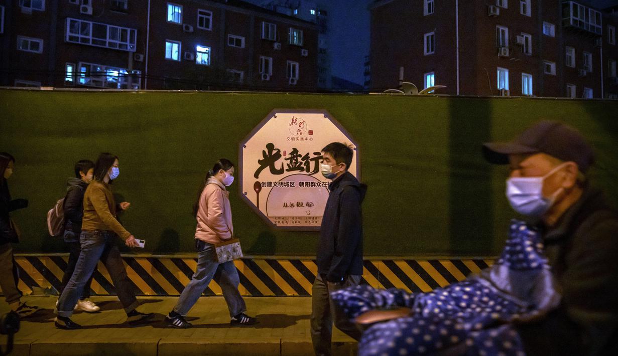 Komuter yang mengenakan masker berjalan di sepanjang jalan di Beijing, Rabu (2/11/2022). Para pekerja iPhone Apple Inc meninggalkan pabrik karena lokasinya berada dalam zona industri Kota Zhengzhou yang sedang diberlakukan lockdown setelah adanya 64 laporan kasus virus corona di kawasan tersebut. (AP Photo/Mark Schiefelbein)