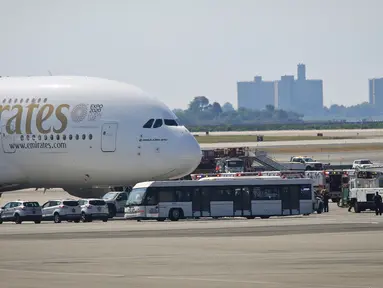 Petugas tanggap darurat berkumpul di luar pesawat setelah penumpang Emirates Airline dilaporkan jatuh sakit di Bandara Kennedy New York, Rabu (5/9). Sekitar 100 dari total 500 penumpang pesawat dari Dubai itu mengeluh sakit dan demam. (AP/Bebeto Matthews)