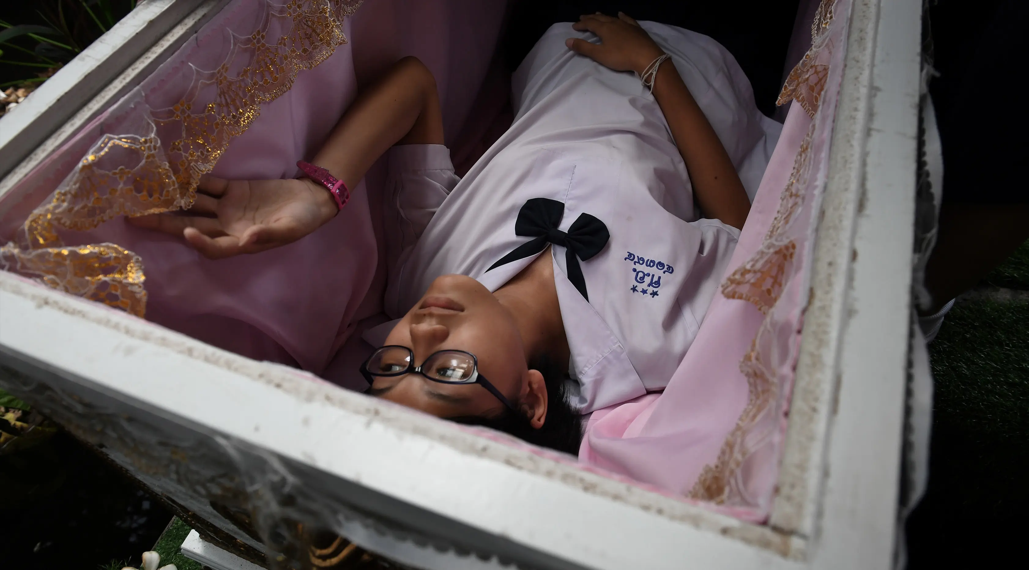 Seorang siswa remaja berbaring di dalam peti mati di Kid Mai Death Awareness Cafe, Thailand (30/3). Cafe ini menyediakan ruang pameran yang dibangun untuk mendidik masyarakat tentang kematian dan agama Buddha di Bangkok. (AFP/Lillian Suwanrumpha)