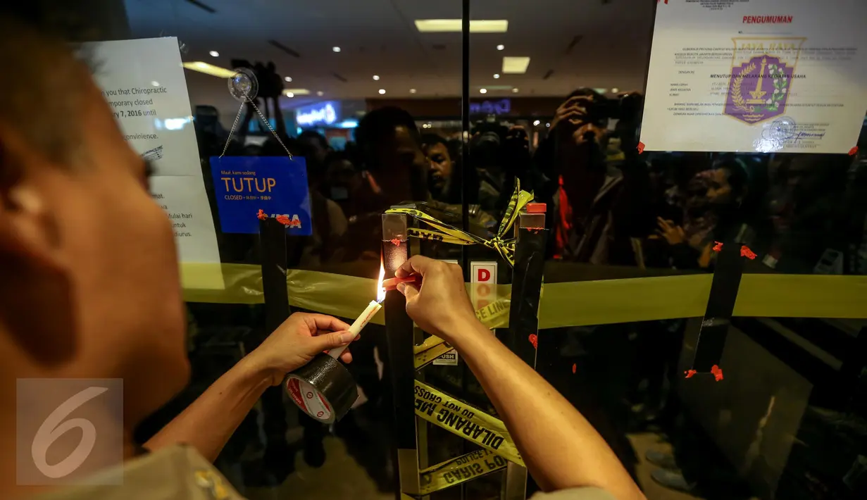 Sejumlah wartawan mengambil gambar petugas Satpol PP yang tengah menyegel  klinik Chiropractic First yang tidak memiliki izin, di pusat perbelanjaan Grand Indonesia, Jakarta, Rabu (13/1). (Liputan6.com/Faizal Fanani)
