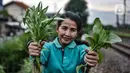Wiwin (51) menunjukkan sayur hasil panen di Kebun Kesehatan, RT 004/008, Cipinang Lontar, Jakarta, Senin (8/3/2021). Wiwin berharap pemerintah terkait dapat mendukung penuh agar lingkungan bantaran rel kereta di Jakarta menjadi lebih bermanfaat. (merdeka.com/Iqbal S Nugroho)