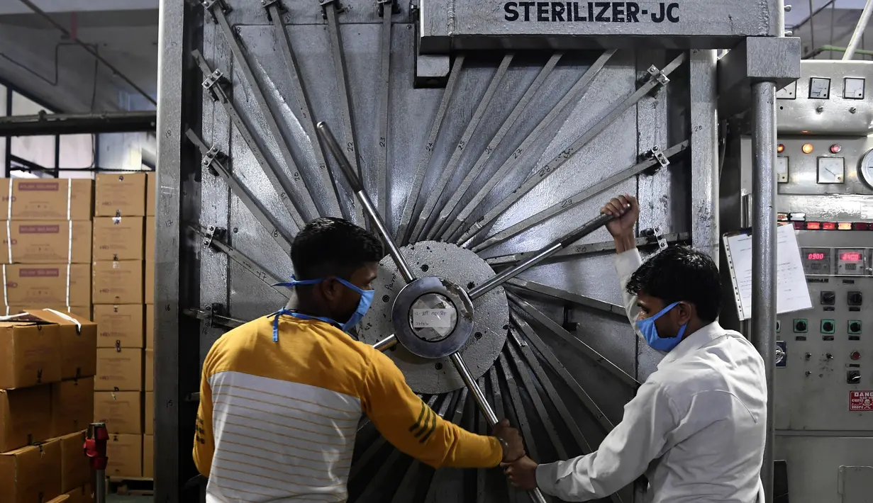 Para pekerja mengunci pintu ruang sterilisasi di pabrik Jarum Suntik Hindustan di Faridabad (2/9/2020). Produsen jarum suntik terbesar di India meningkatkan produksinya untuk menghasilkan satu miliar unit. (AFP/Sajjad Hussain)