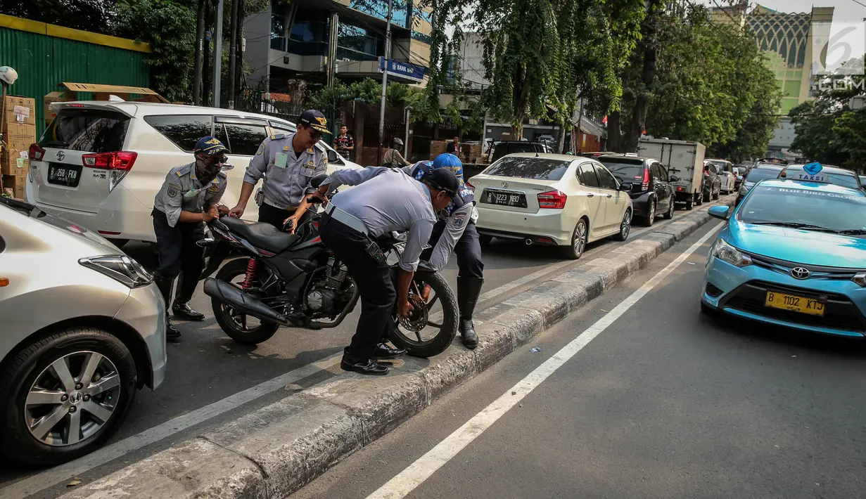 Petugas Dishub mengangkut sepeda motor saat melakukan penertiban parkir liar di atas trotoar kawasan KH Wahid Hasyim, Jakarta, Selasa (1/8). Penertiban dalam rangka Bulan Patuh Trotoar itu untuk mengembalikan fungsi trotoar. (Liputan6.com/Faizal Fanani)
