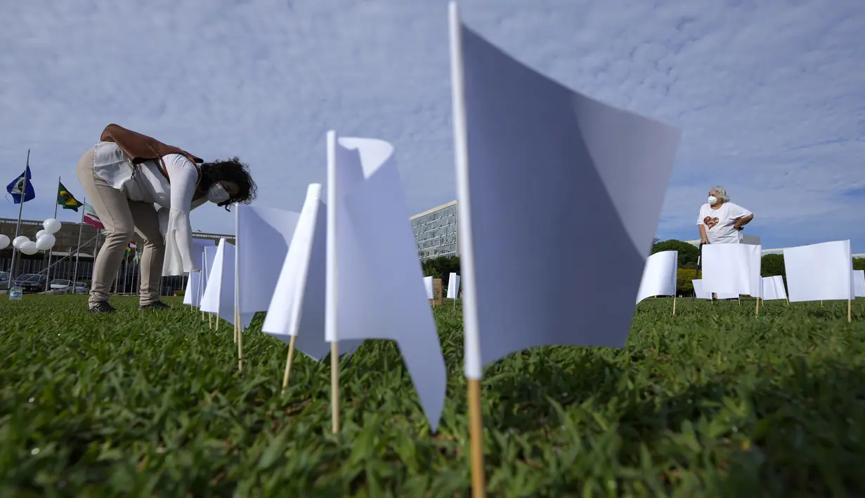 Bendera putih menutupi lapangan sebagai bagian dari protes terhadap kebijakan kesehatan pemerintah di luar Kongres di Brasilia, Jumat (15/10/2021). Sebanyak 600 bendera, masing-masing dengan nama seseorang, mewakili 600.000 korban yang telah meninggal COVID-19 di Brasil. (AP Photo/Eraldo Peres)