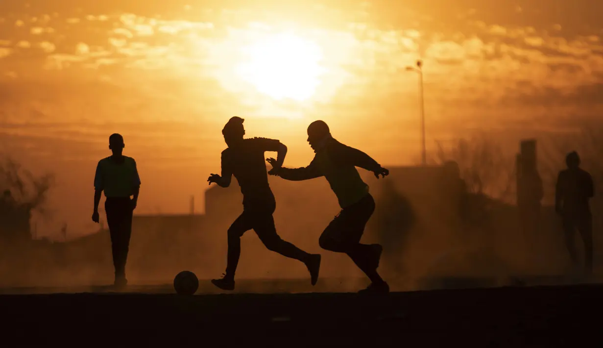 Orang-orang bermain sepak bola di lapangan berdebu di Soweto, Afrika Selatan, 19 Agustus 2020. Presiden Afrika Selatan Cyril Ramaphosa mengumumkan bahwa seluruh negara akan melakukan lockdown level 2 mulai hari Selasa. (AP Photo/ Themba Hadebe)