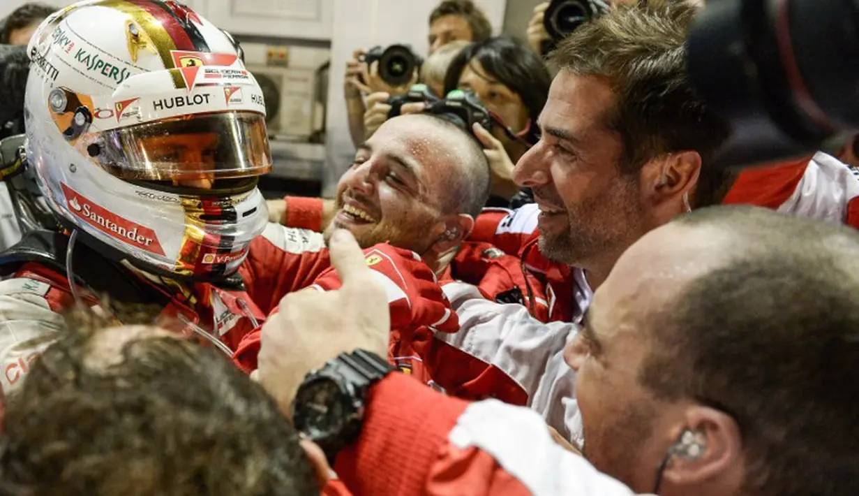 Sebastian Vettel disambut kru tim Ferrari setelah memenangi balapan F1 GP Singapura di Sirkuit Marina Bay, Singapura, Minggu (20/9/2015). (AFP Photo/Mohd Rasfan)