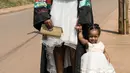 Seorang wisudati membawa anaknya untuk mengikuti upacara wisuda ke-68 di Universitas Makerere di Kampala, Uganda (19/1). Upacara wisuda tersebut diikuti lebih dari 14.000 mahasiswa. (AFP Photo/Michele Sibiloni)