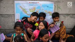 Sejumlah anak-anak berdiskusi sambil menuliskan cita-cita mereka di jalur banjir kanal barat Tanah Abang, Jakarta, Senin (31/7). Kegiatan tersebut sebagai bentuk harapan mereka dalam rangka peringati hari anak nasional. (Liputan6.com/Faizal Fanani)