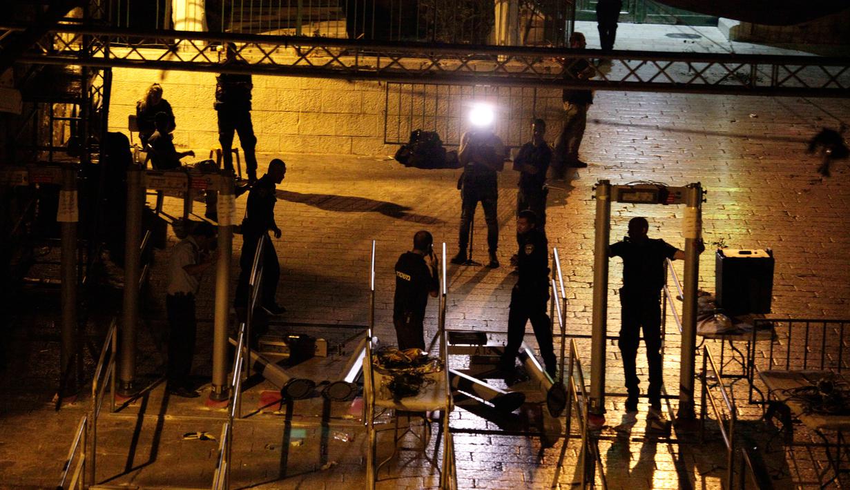 Pekerja membongkar detektor logam di luar kompleks Masjid Al Aqsa, Yerusalem, Selasa (25/7) dini hari. Keputusan ini diambil setelah desakan dari berbagai pihak terhadap Israel untuk meredakan ketegangan di Al Aqsa dan Tepi Barat (AP Photo/Mahmoud Illean)