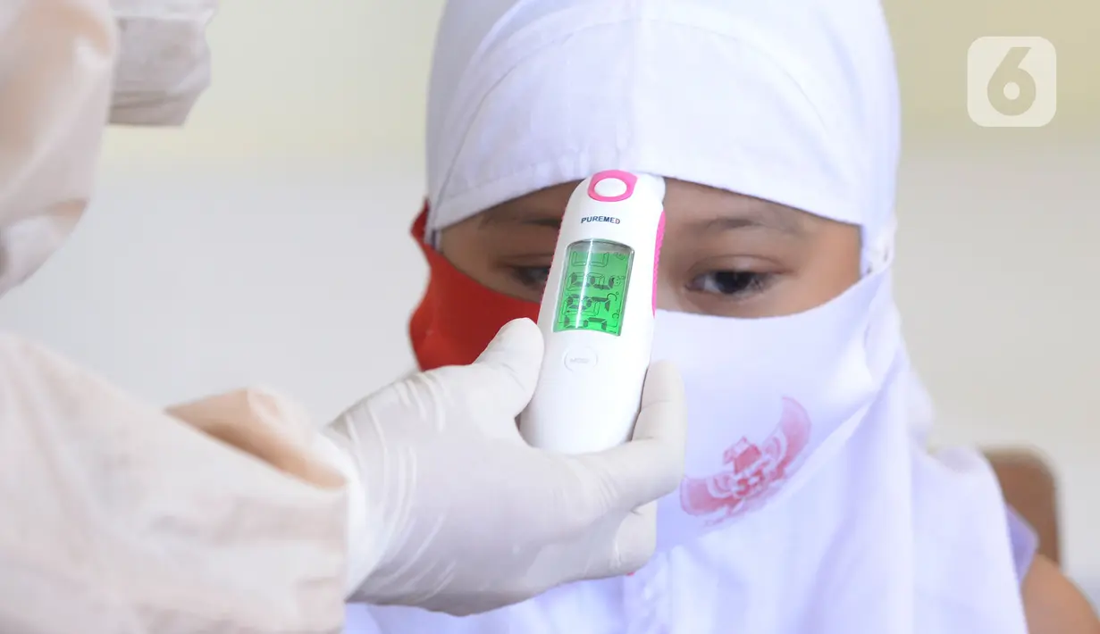 Siswa kelas I diukur suhu tubuhnya sebelum melakukan imunisasi campak saat pelaksanaan Bulan Imunisasi Anak Sekolah (BIAS) di SDN Serua 3, Ciputat, Tangsel, Selasa (1/9/2020). Kegiatan itu untuk memberikan kekebalan terhadap siswa dari penyakit campak, difteri dan tetanus. (merdeka.com/Dwi Narwoko)