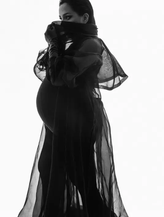 Lakukan maternity shoot, Angel tampak dramatis dalam gaun hitam see through yang hadirkan keindahan siluet. [Foto: Instagram/ Angel Pieters]