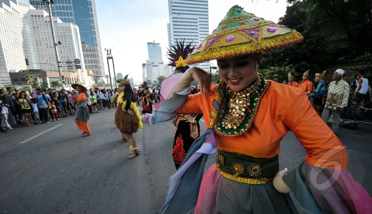 Sejumlah warga menyaksikan Aksi menari Mahasiswa saat car free day di Bundara HI, Jakarta, Minggu (26/4/2015). Mereka meminta sumbangan kepada warga untuk mengikuti Interntional Folklore Festival di Spanyol. (Liputan6.com/Faizal Fanani)