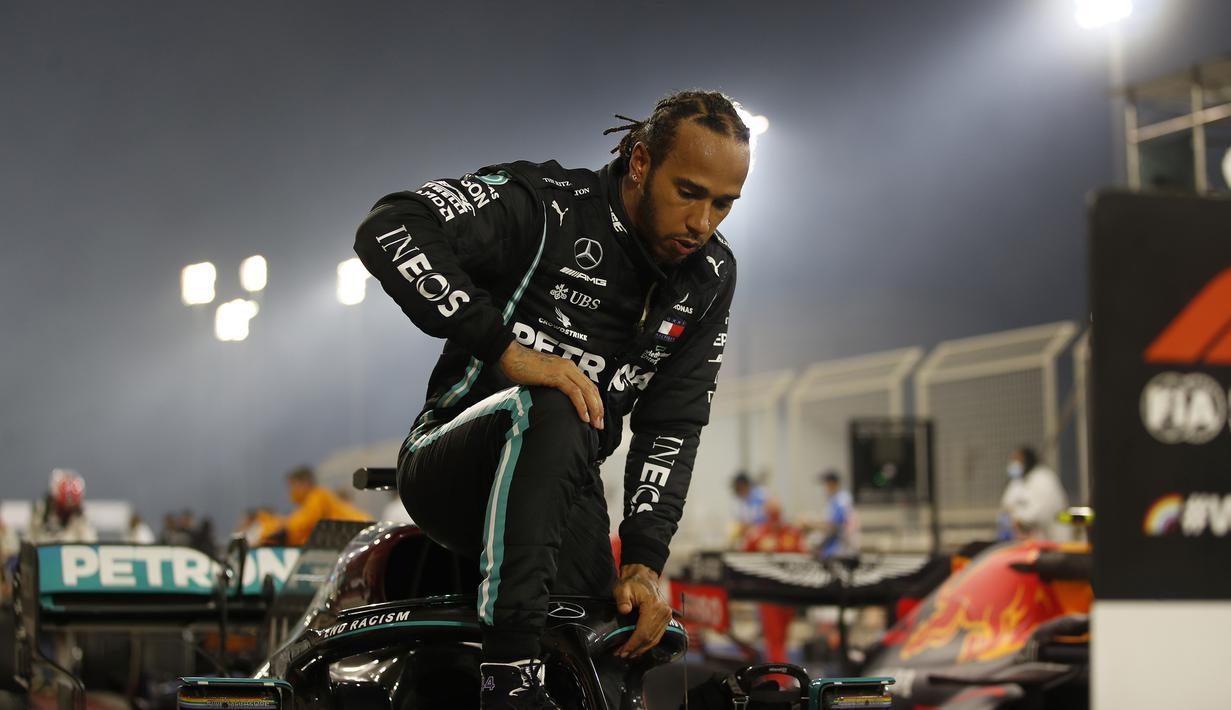 Pembalap Mercedes asal Inggris, Lewis Hamilton berlutut saat keluar dari mobilnya, sebagai dukungan kampanye gerakan Black Lives Matter, usai memenangi Grand Prix Formula Satu Bahrain di Sirkuit Internasional Bahrain, Sakhir, Minggu, (29/11/2020). (AFP/Hamad I Mohammed)