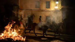 Orang-orang menunggangi kuda melewati api unggun selama festival Luminarias di San Bartolome de Pinares, Spanyol, Rabu (16/1). Festival yang digelar setiap tahunnya pada tanggal 16 Januari ini mulai dilaksanakan sekitar 500 tahun lalu. (AP/Felipe Dana)