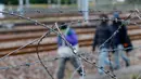 Sejumlah imigran terlihat dari balik pagar berduri sedang berjalan dekat rel kereta di Coquelles dekat Calais di Prancis, 29 Juli 2015. Ribuan imigran tersebut mencoba memasuki Terowongan Channel menuju Inggris melalui Prancis. (REUTERS/Pascal Rossignol)