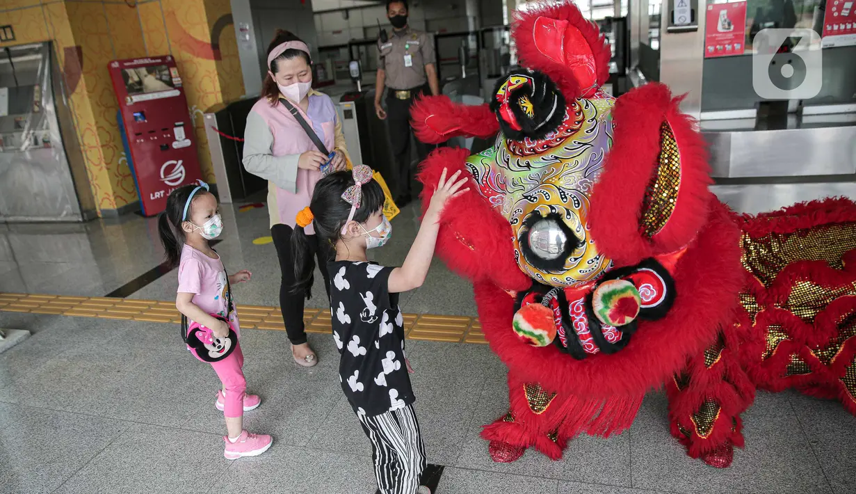 Seorang anak memegang Barongsai yang melakukan atraksi di Stasiun LTR Velodrome, Jakarta, Selasa (1/2/2022). Atraksi Barongsai tersebut bertujuan untuk menghibur penumpang LRT dalam rangka menyambut Tahun Baru Imlek. (Liputan6.com/Faizal Fanani)