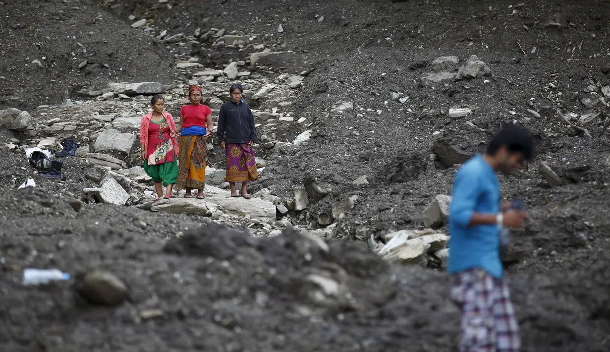Sejumlah orang mengamati daerah yang terkena longsor di Desa Lumle, Nepal (30/7/2015). Tanah longsor yang dipicu hujan deras tersebut menewaskan sedikitnya 30 orang dan menghacurkan puluhan rumah. (REUTERS/Navesh Chitrakar)