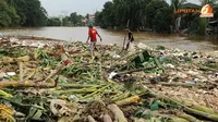 Mereka pun harus berjalan cukup jauh ke tengah untuk lebih banyak mengumpulkan sisa barang-barang yang hanyut terbawa derasnya arus sungai Ciliwung (Liputan6.com/Helmi Fithriansyah).
